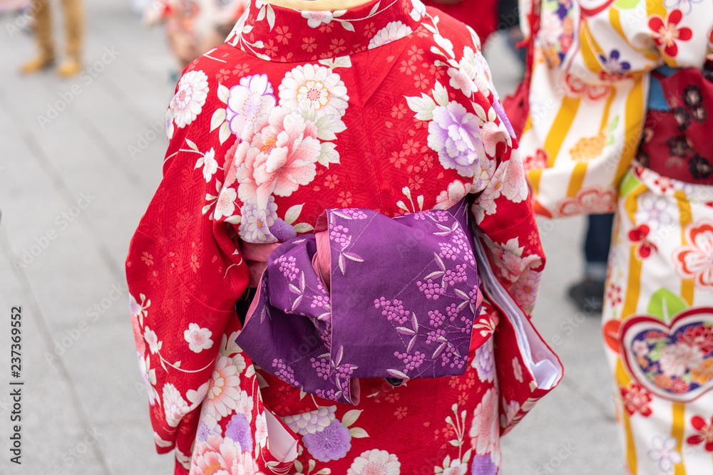Naklejka premium Young girl wearing Japanese kimono standing in front of Sensoji Temple in Tokyo, Japan. Kimono is a Japanese traditional garment. The word