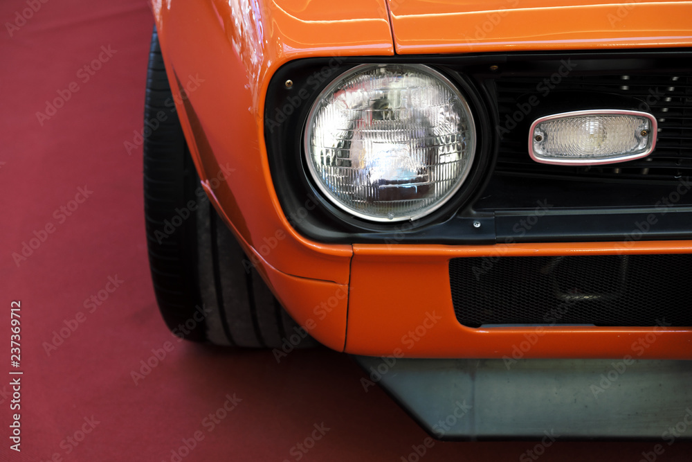 Closeup headlights of an orange retro car.