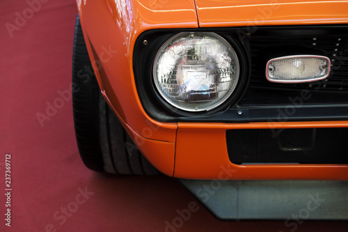 Closeup headlights of an orange retro car. © spaskov
