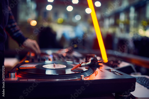 turntable, hand of dj on the vinyl record at night club. blured background