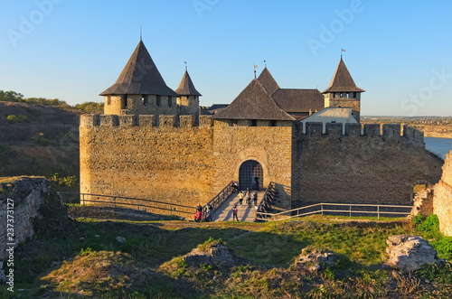 Charming Khotyn Fortress in autumn sunny day. The tourists go through the bridge to the fortress. Famous touristic place and travel destination in Ukraine. Khotyn. Chernivtsi region. Ukraine
