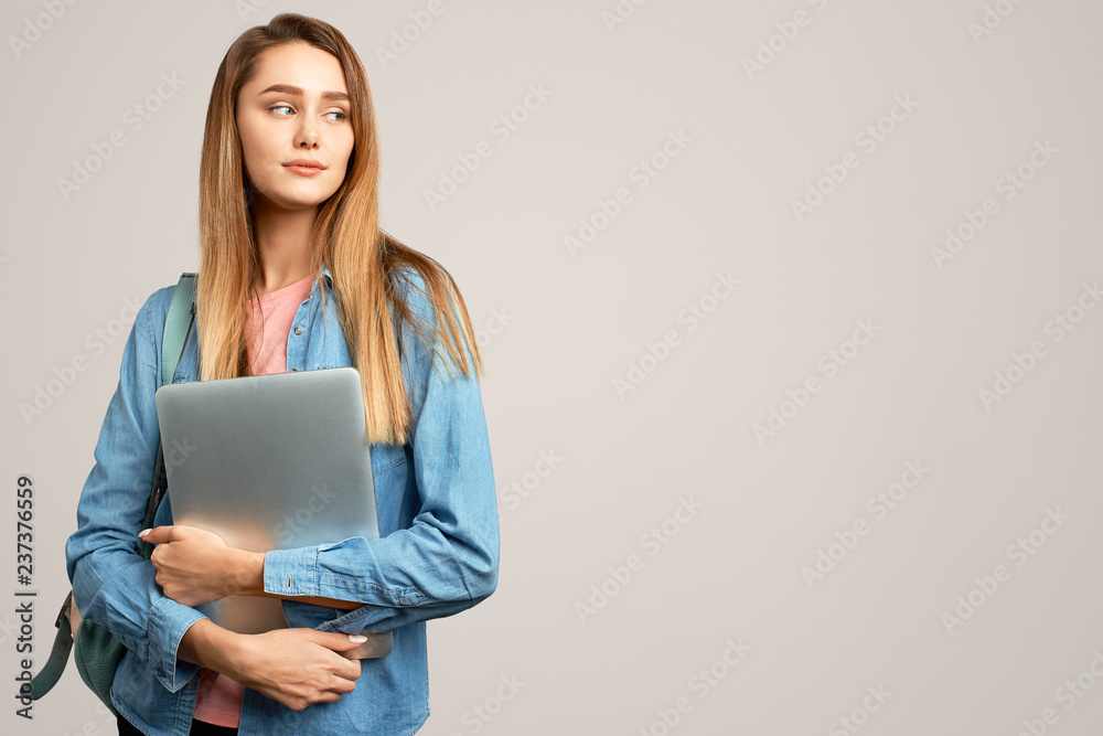 Φωτογραφία Attractive blonde girl in a blue denim shirt holding a laptop and looking away
