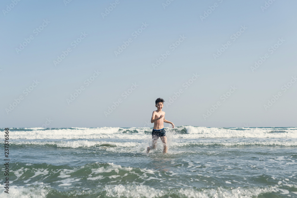 Boy Jumping In Sea Waves with Water Splashes. Concept of summer vacation Boy Jumping In Sea Waves with Water Splashes. Concept of summer vacation
