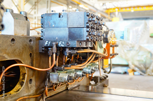 The hydraulic system on the machine  copper oil tubes connected to the equipment in production. Bed for guides under the influence of the hydraulic system. Abstract industrial background.