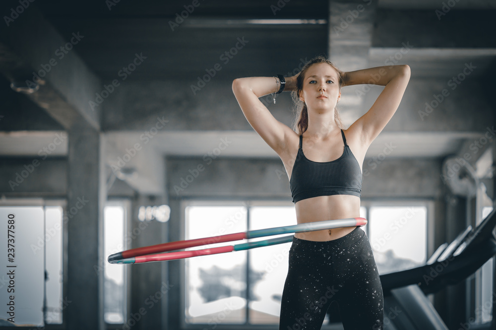 Beautiful caucasian young woman doing hula hoop in step waist hooping forward stance. Young woman doing hula hoop during an exercise class in a gym. Healthy sports lifestyle, Fitness, Healthy concept. Beautiful caucasian young woman doing hula hoop in step waist hooping forward stance. Young woman doing hula hoop during an exercise class in a gym. Healthy sports lifestyle, Fitness, Healthy concept.