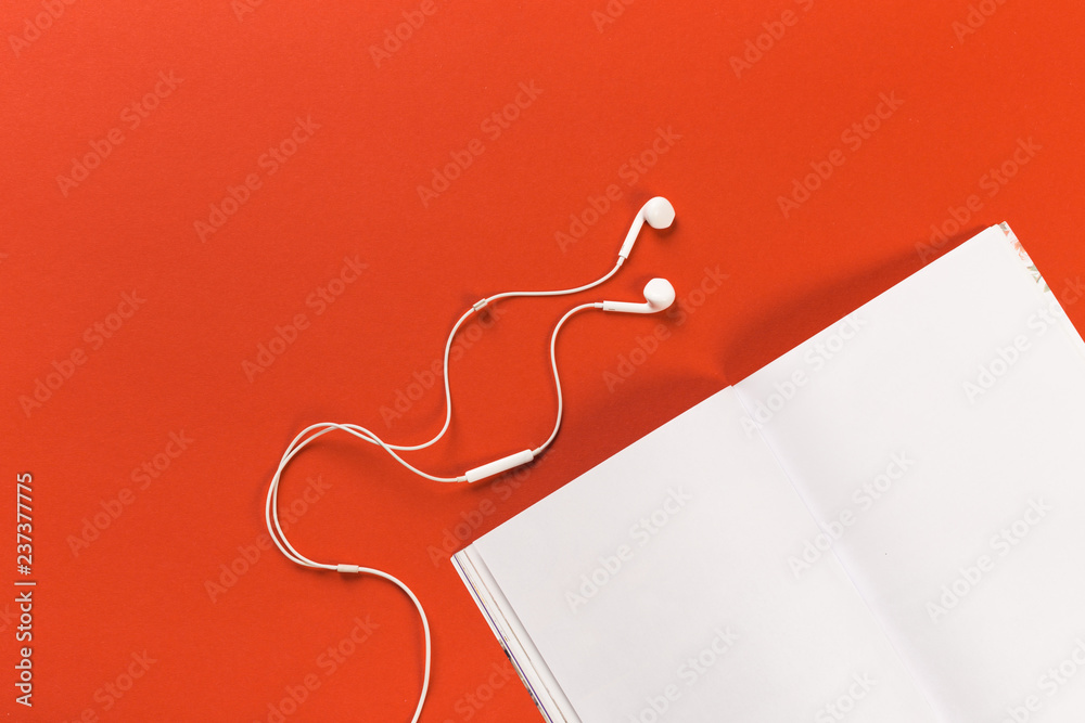 white headphones and a mocup magazine on a red background white headphones and a mocup magazine on a red background