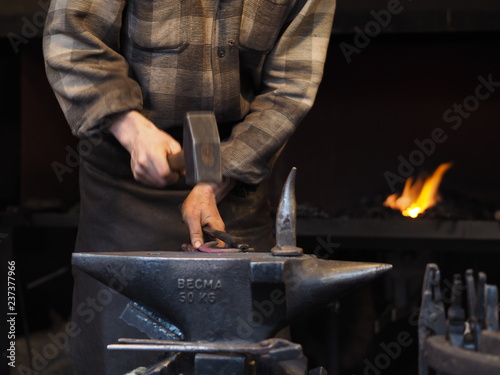 Blacksmith working metal with hammer in the forge for good luck on a christmas market in Cologne.