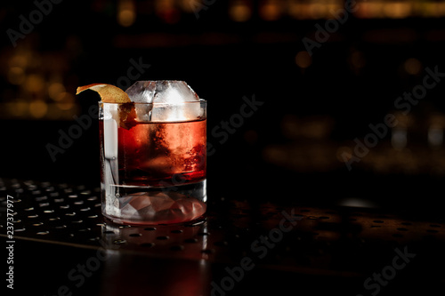 Glass of a Boulevardier cocktail with orange zest on the steel bar counter photo