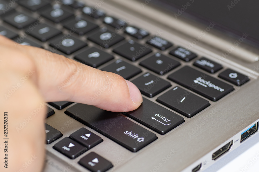 Press the enter key of a laptop computer with index finger Press the enter key of a laptop computer with index finger