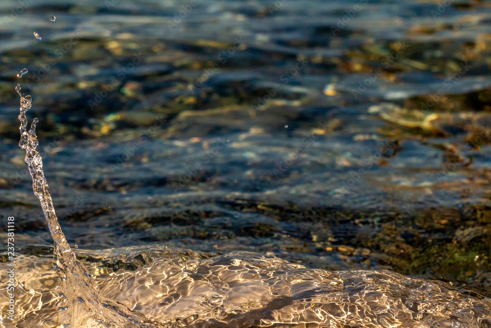 Splash of sea water. Clear sea, the play of light in the droplets. Glare and blurred background. Splash of sea water. Clear sea, the play of light in the droplets. Glare and blurred background.