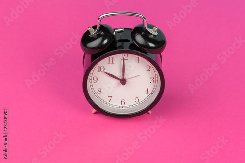 Vintage black alarm clock on lilac background