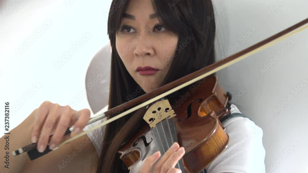Woman of asian appearance playing a violin. Close up Woman of asian appearance playing a violin. Close up