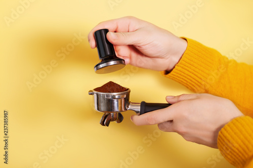 Man is using a tamper to press freshly ground morning coffee into a coffee tablet.
