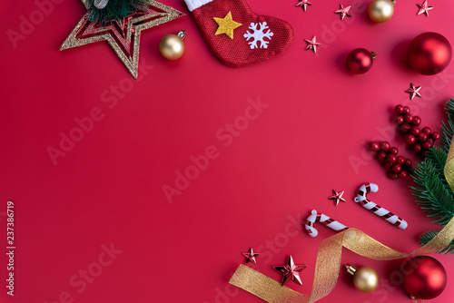 Christmas background concept. Top view of Christmas socks and gift box with spruce branches, pine cones, red berries and bell on red background.
