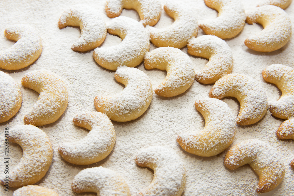 German and Austrian traditional Christmas cookies vanilla crescents on white tray powdered with castor sugar. Beautiful light. Food pattern. Holiday baking concept