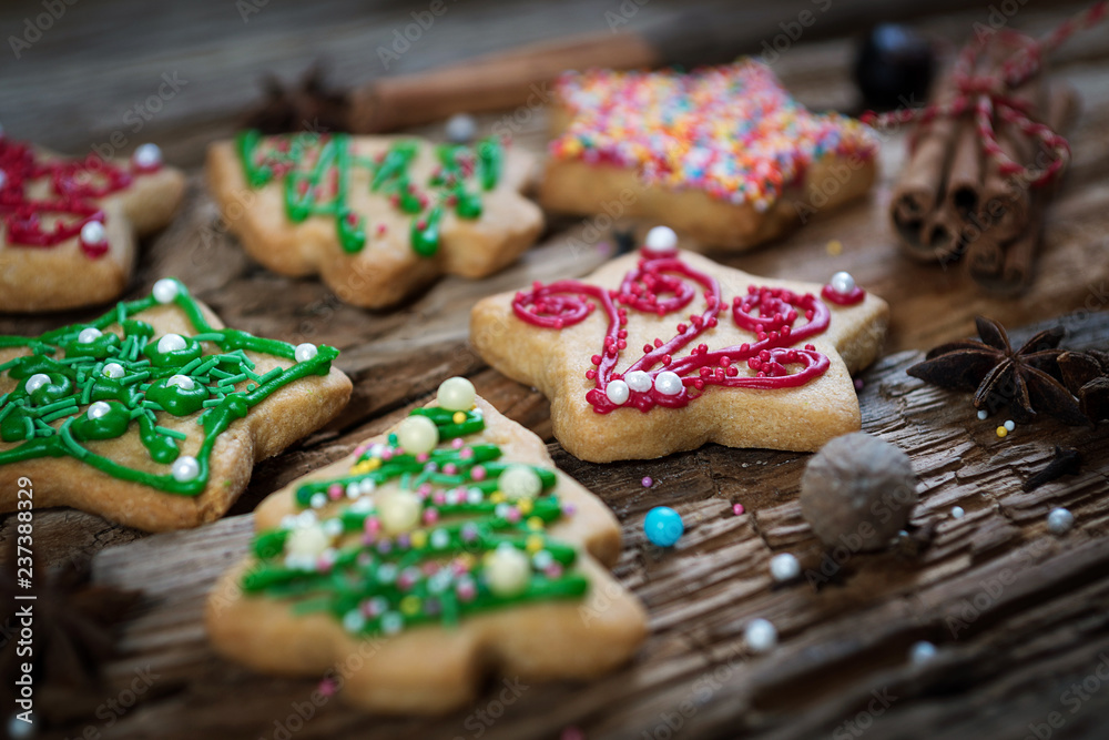 gingerbread in the form of Christmas trees, stars and red-green on a wooden background with cinnamon and star anise