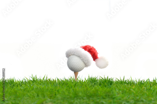 Festive-looking golf ball on tee with Santa Claus' hat on top for holiday season isolated on white background