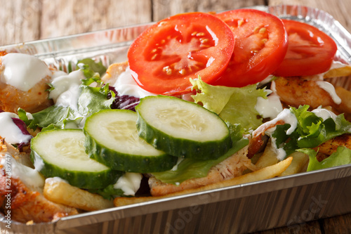 Recipe Dutch fast food kapsalon of french fries, chicken, fresh salad, cheese and sauce close-up. horizontal