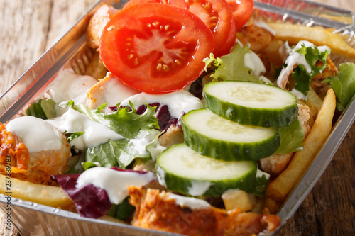 Traditional Dutch fast food kapsalon of french fries, chicken, fresh salad and sauce close-up. Horizontal