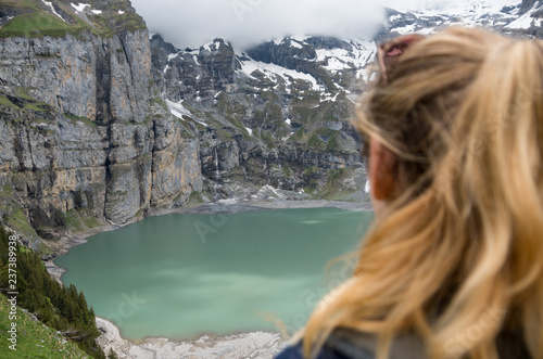 Young beautiful woman lookiing over glacial mountain lake with the focus on the landscape photo