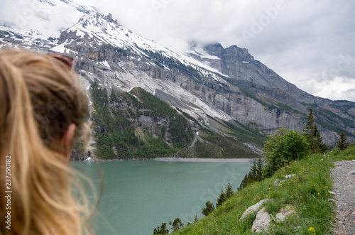 Young beautiful woman lookiing over glacial mountain lake with the focus on the landscape
