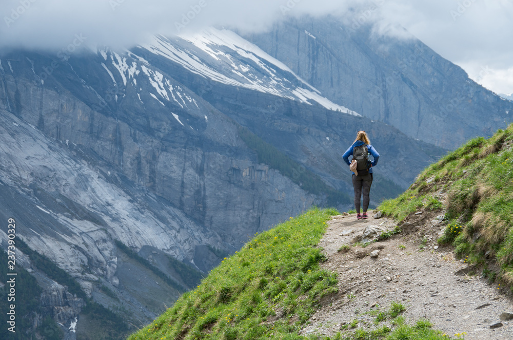 Young beautiful woman standing on a mountain path looking out over the range Young beautiful woman standing on a mountain path looking out over the range