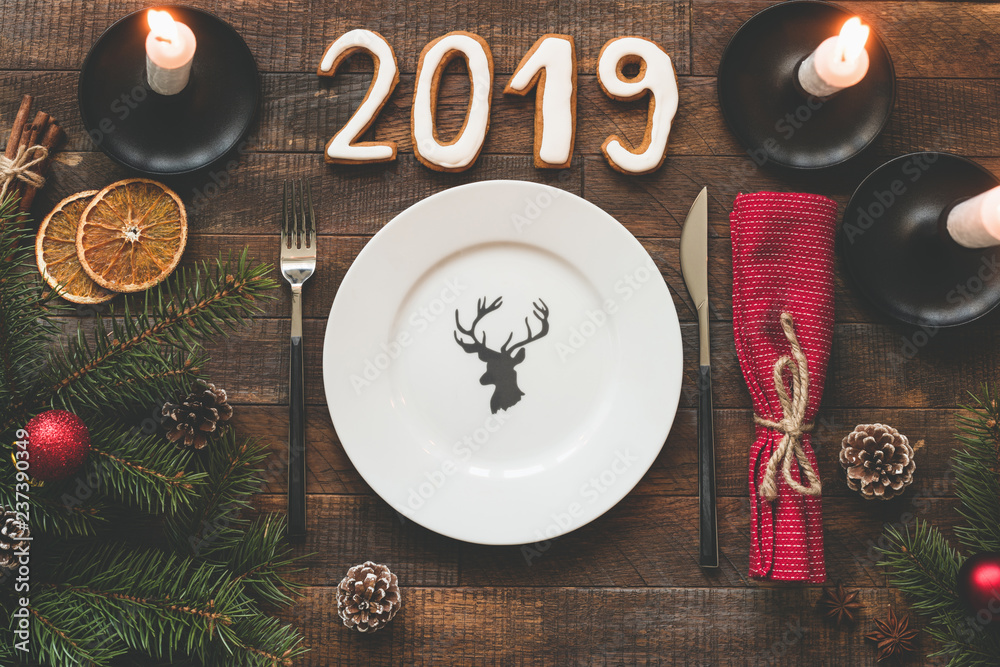 Table setting for Christmas or New Year 2019. Empty plate, silverware, red textile and candles on rustic wooden background Table setting for Christmas or New Year 2019. Empty plate, silverware, red textile and candles on rustic wooden background
