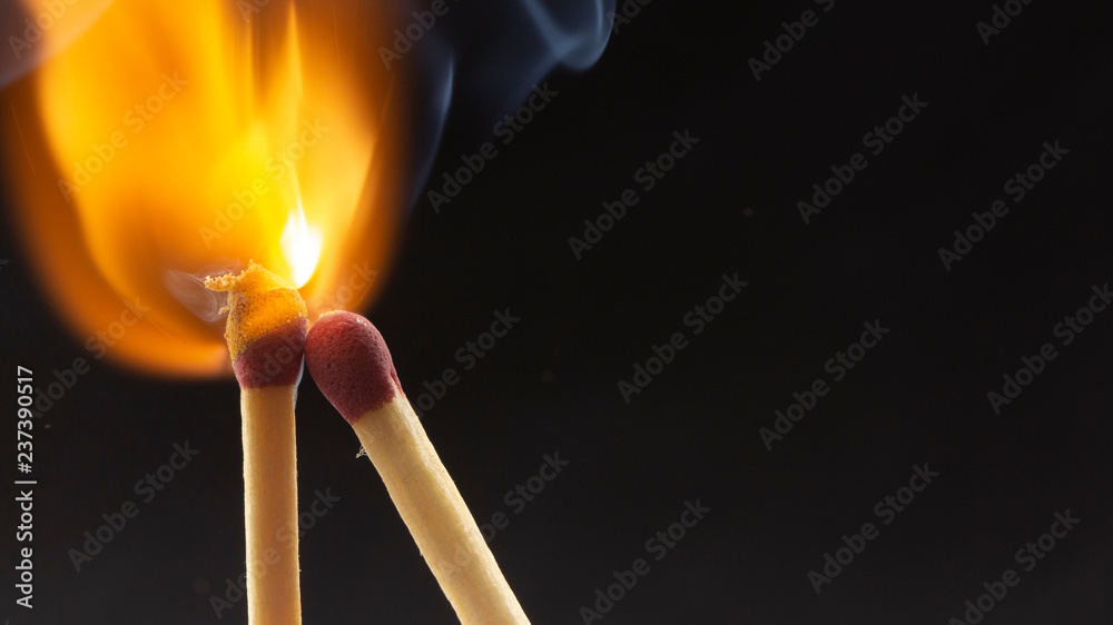 Burning wooden match with a red match head on a black background. Burning wooden match with a red match head on a black background.