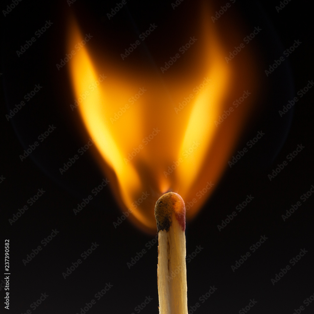 Burning wooden match with a red match head on a black background. Burning wooden match with a red match head on a black background.