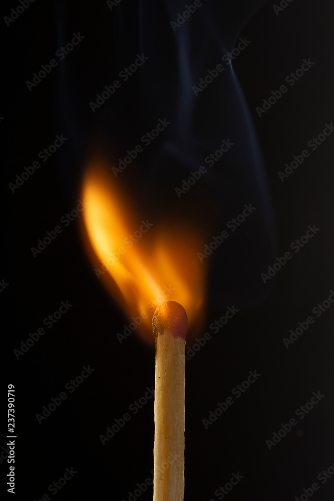 Burning wooden match with a red match head on a black background. Burning wooden match with a red match head on a black background.