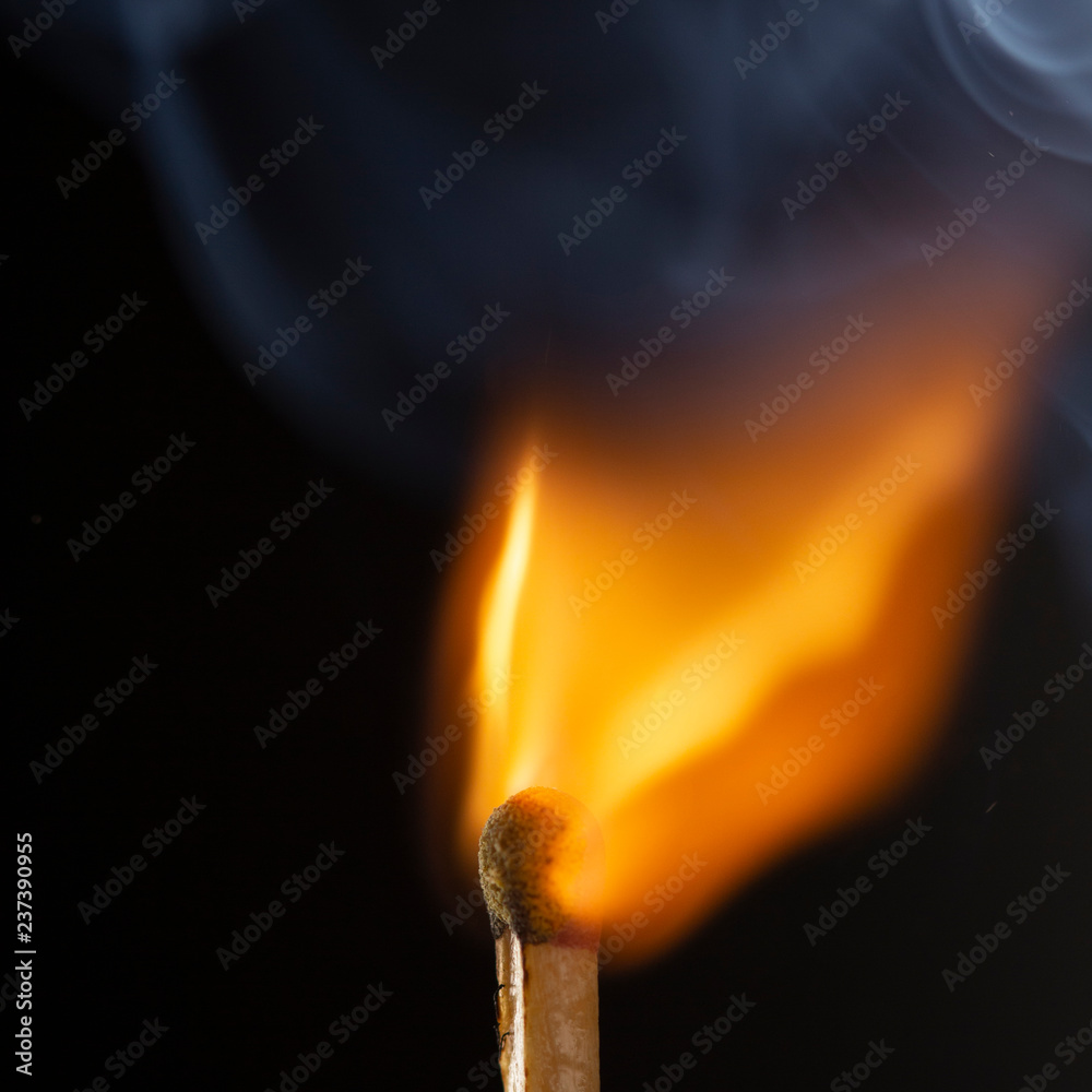 Burning wooden match with a red match head on a black background. Burning wooden match with a red match head on a black background.