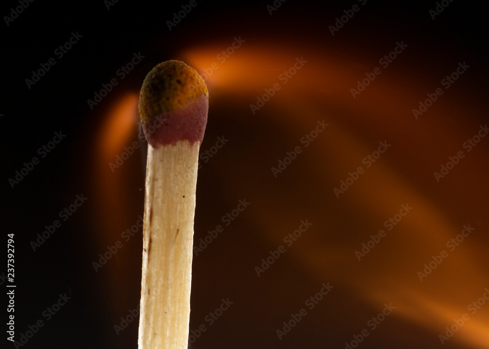 Burning wooden match with a red match head on a black background. Burning wooden match with a red match head on a black background.