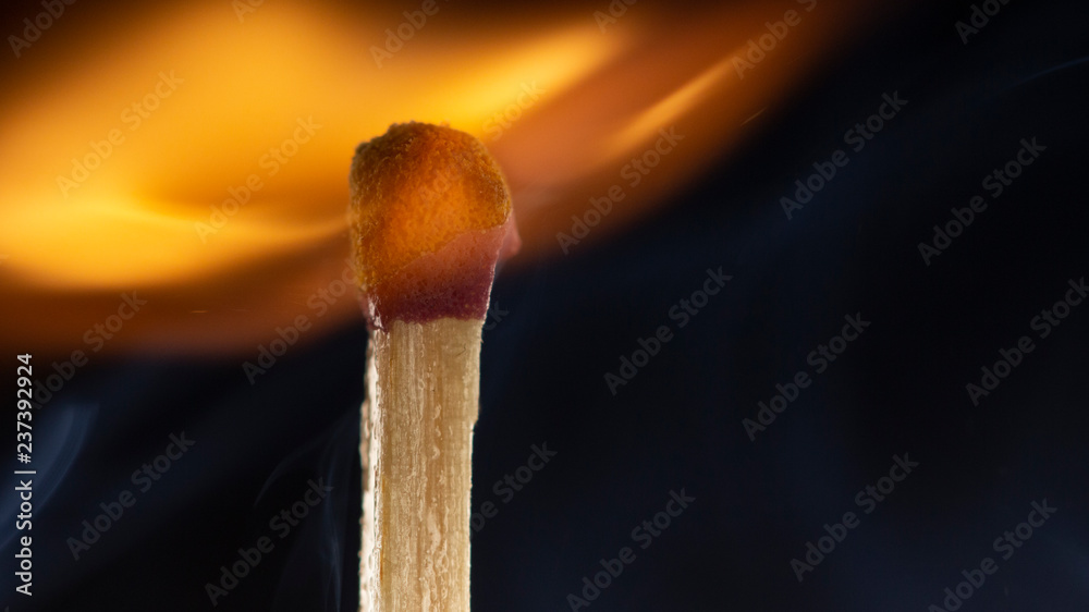 Burning wooden match with a red match head on a black background. Burning wooden match with a red match head on a black background.