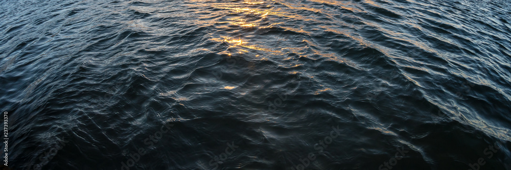 Water waves and orange sun light reflection