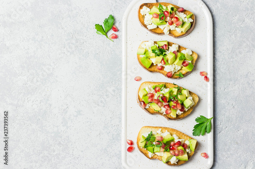 Avocado feta cheese pomegranate seeds crostini. Top view, space for text.