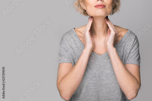 Fototapeta Female checking thyroid gland by herself