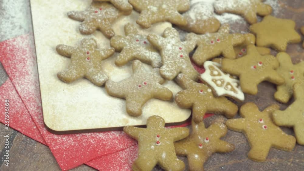 Gingerbread men sprinkled with powdered sugar and lie on a brown wooden table Gingerbread men sprinkled with powdered sugar and lie on a brown wooden table