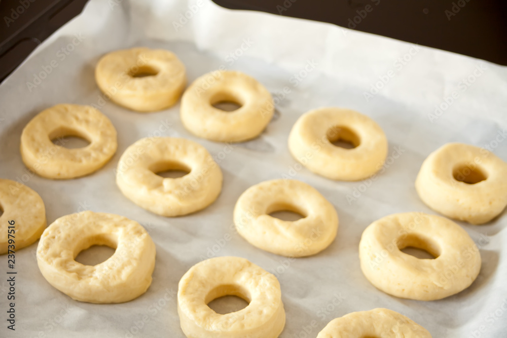 Raw donuts on the baking paper and tray