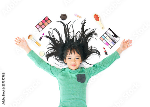 Little asian girl lying with cosmetics around her head and isolated on white background