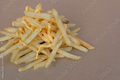 Unhealthy junk food, group of cheesy french fries on brown paper with blank space, fast food concept