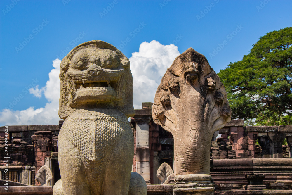 Fototapeta premium Close up of old lion sculpture and old snake sculpture at the historic site in Thailand with blue sky and cloud background. 