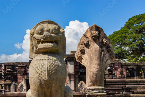 Close up of old lion sculpture and old snake sculpture at the historic site in Thailand with blue sky and cloud background. 