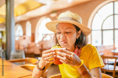 Young woman drinking coffee or tea from paper cup in cafe