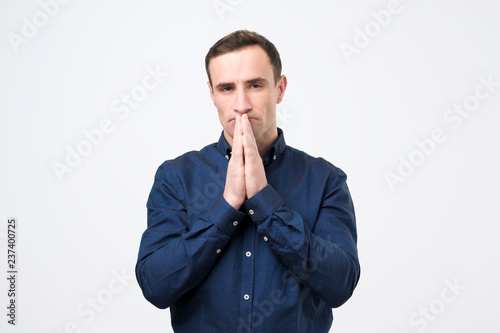 Desperate young man showing clasped hands, asking for help
