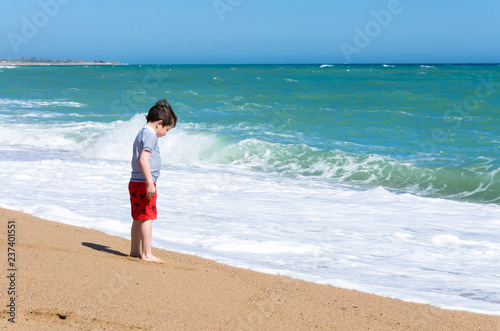 A boy plays on a sandy beach at the water's edge © Matthew Ashmore