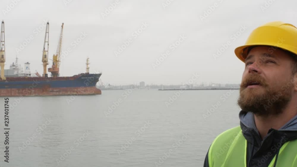 seaport worker with a beard and a helmet on the background of ships seaport worker with a beard and a helmet on the background of ships