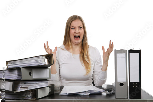 Frau sitzt an einem vollen Schreibtisch und schaut verzweifelt photo