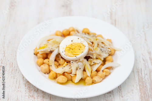 chick-pea with cod fish and boiled egg on white plate