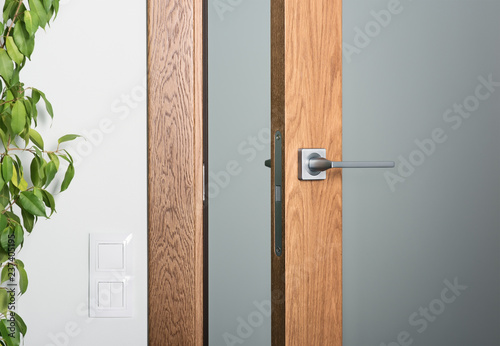 Close-up of ajar door. Steel door handle, dark textured wood