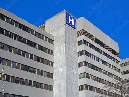 Large concrete building with  H sign for hospital